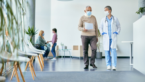 Senior patient with neck collar and his doctor analyzing medical report while walking through hallway at the hospital.