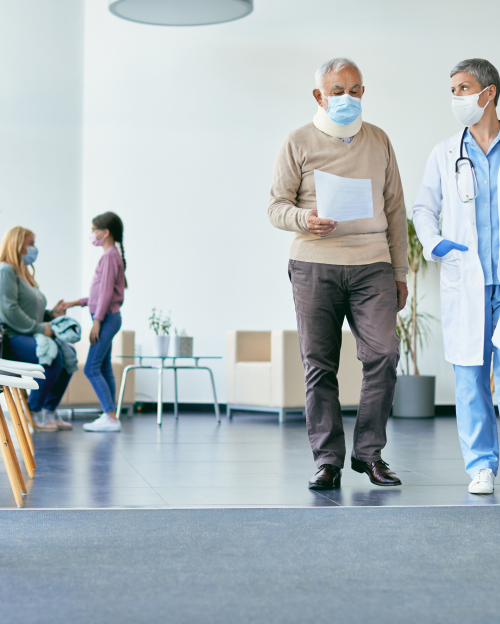 Senior patient with neck collar and his doctor analyzing medical report while walking through hallway at the hospital.