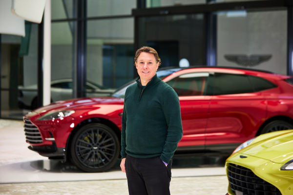 Image of Martin Corner, from the knees up, stood in front of a red Aston Martin DBX